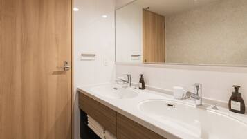 A modern bathroom with two sinks, a large mirror, and wooden cabinetry.
