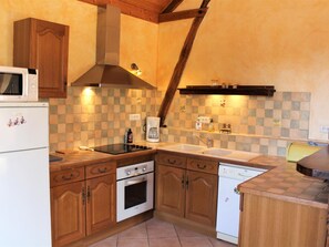 A kitchen with wooden cabinets, a microwave, an oven, a dishwasher, and a checkered backsplash.