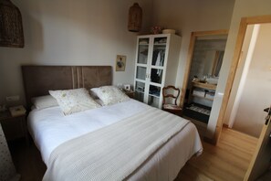 Une chambre à coucher avec un grand lit, une armoire, une table de chevet et un miroir.