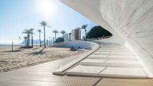 A beachside promenade with a curved pathway, palm trees, and a view of the sea and mountains in the background. - Sunset Waves 18-35 Poniente Beach Resort (Benidorm)