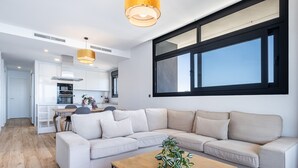 A modern living room with a beige sectional sofa, a wooden coffee table with a plant, and a large window with black frames. - Sunset Waves 18-35 Poniente Beach Resort (Benidorm)