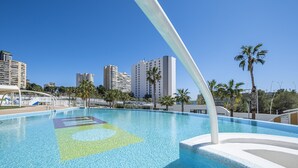 A clear blue swimming pool with a geometric design on the floor, surrounded by palm trees and modern buildings in the background. - Sunset Waves 18-35 Poniente Beach Resort (Benidorm)