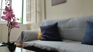 A living room with a striped sofa, a potted orchid, and a beach-themed wall art. - Best Location. Playa Las Vistas. Free Wifi (Playa de la Américas)