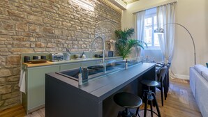 A modern kitchen with a stone wall, a bar area, and a seating arrangement. - " PALAZZO OF LORDS " LUXURY & DESIGN LOFT/APT WITH VIEW, FLORENCE (Firenze)
