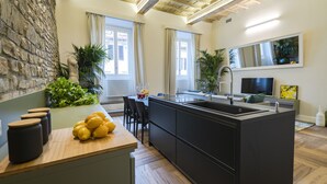 A modern kitchen with a central island, black cabinetry, and a stone accent wall. - " PALAZZO OF LORDS " LUXURY & DESIGN LOFT/APT WITH VIEW, FLORENCE (Firenze)