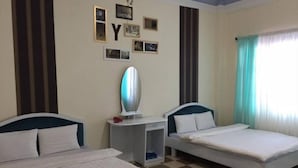 A hotel room with two beds, a small desk, and a wall decorated with framed pictures and letters. - Minh Duc Hotel (Cam Ly - Da Lat)