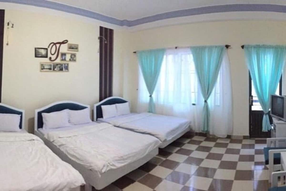 A room with three beds, a television, and a checkered floor.