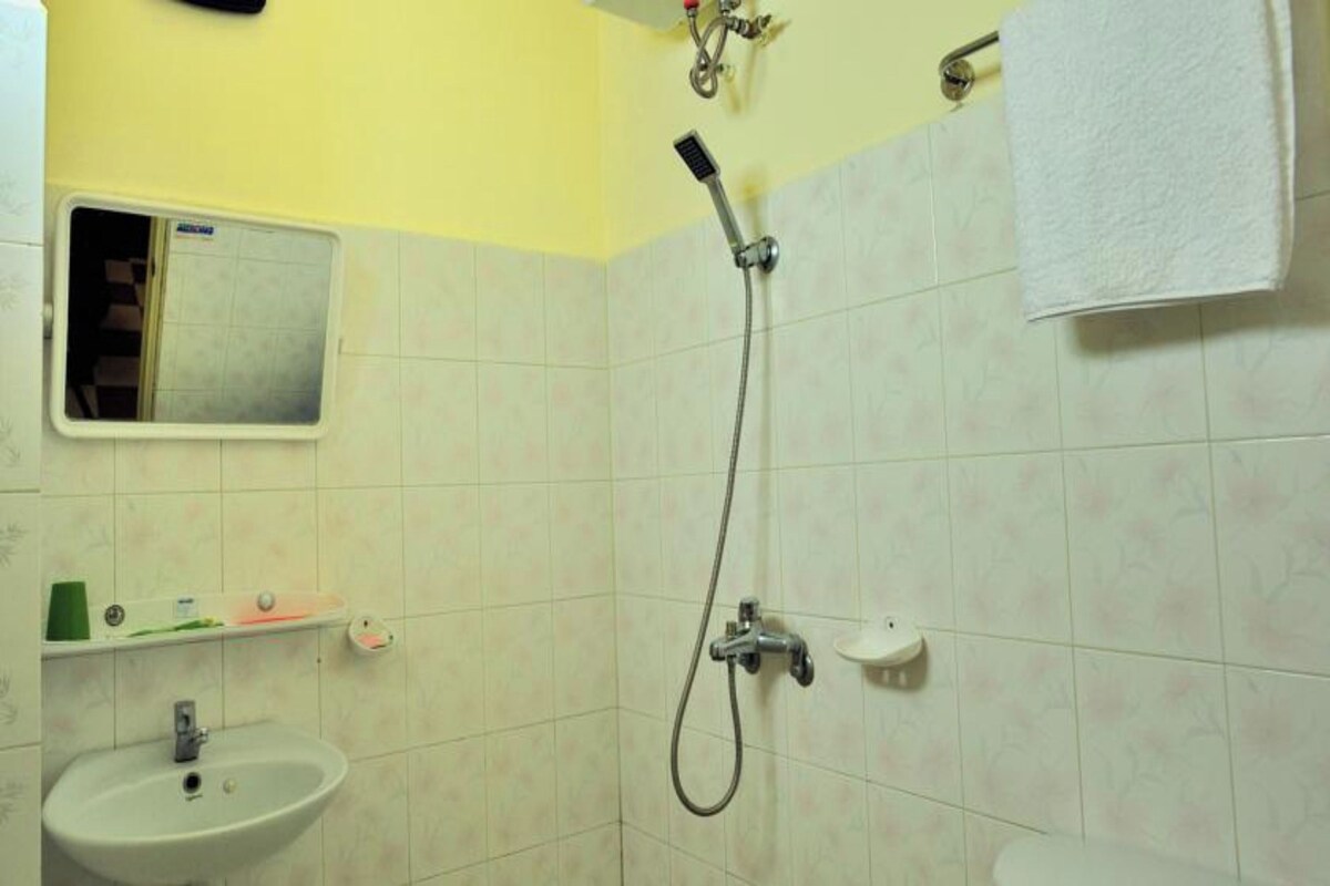 A bathroom with a sink, mirror, shower, and toilet.