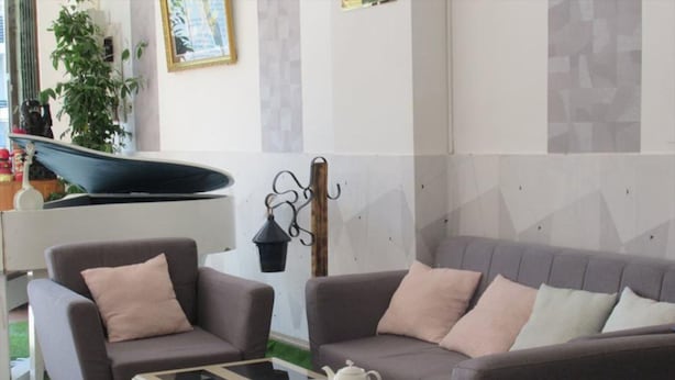 A living room with a gray sofa, two armchairs, a coffee table, and a television. - Minh Duc Hotel (Cam Ly - Da Lat)