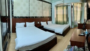 A hotel room with two beds, a wooden desk, a chair, a TV, and a window with curtains.