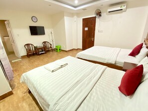 Una habitación de hotel con dos camas, televisión, reloj y aire acondicionado.