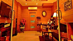 Um quarto bem iluminado, com lambris, um candelabro, um relógio e uma área de jantar com mesa e cadeiras.