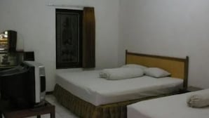 Una cama individual con cabecera de madera en una habitación con paredes blancas.