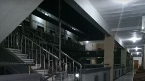 Un pasillo espacioso con una escalera que sube a los pisos superiores, un camino central y una zona de descanso con una silla de mimbre.