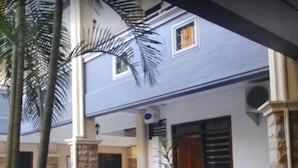 Un edificio con balcón, palmeras y ventana con vistas.