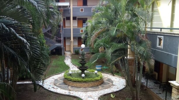 Un patio con una fuente central, rodeado de palmeras y un sendero con diseño.