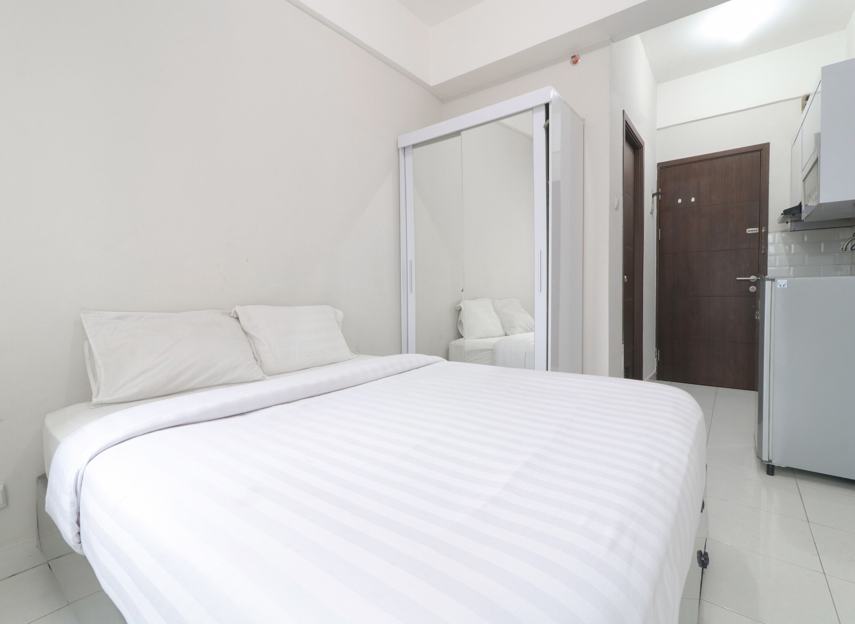 Quarto com cama, guarda-roupa e cozinha compacta.