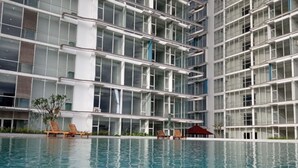 Un edificio moderno con un amplio espacio de piscina, que cuenta con varios niveles de balcones y una vista despejada de la piscina.