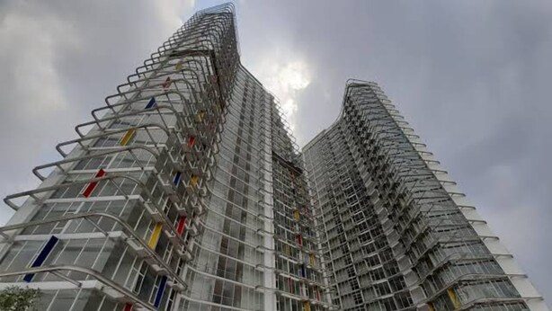 Un edificio alto con un diseño angular distintivo, con varios balcones y fachada de vidrio.