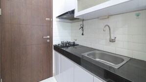 A kitchen with white cabinets, a black countertop, a stainless steel sink, and a gas stove. - Sultan Premiere HI (South Tangerang)