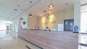 A reception desk at Easton Park apartment with a wooden finish, a clock, and a signboard. - Sultan Premiere HI (South Tangerang)
