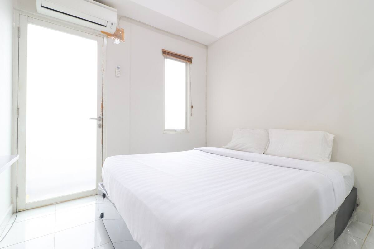 A bedroom with a bed, a window, and an air conditioning unit.