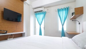 A hotel room with a bed, a mounted TV, an air conditioning unit, and a window with curtains. - Sultan Premiere HI (South Tangerang)