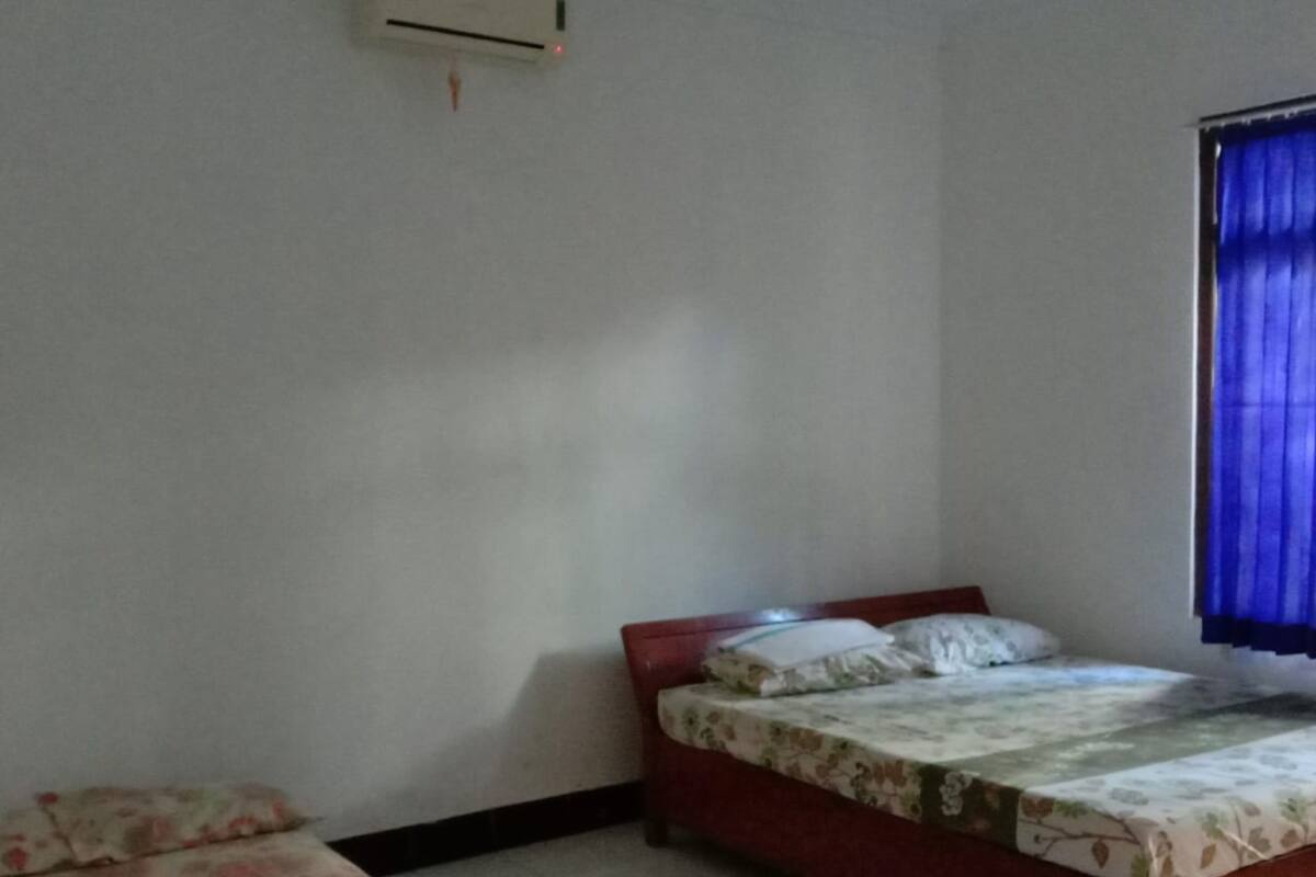 Ein Schlafzimmer mit einem Einzelbett, einem kleineren Bett und einer Klimaanlage an der Wand.