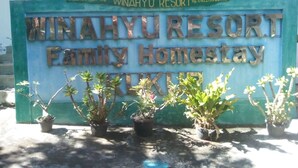 A sign for Winahyu Resort, Family Homestay, with contact numbers and a name in the local language. - Winahyu Family Resort (Wonosari)