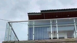 Un edificio con balcón de cristal y techo de metal.