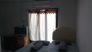 Un dormitorio con una cama individual, un escritorio con computadora y una ventana con cortinas.