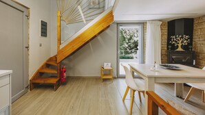 A modern kitchen with a wooden staircase, a dining area with a table and chairs, and a stone fireplace. - Mini Bella Gonia (Rethymno)