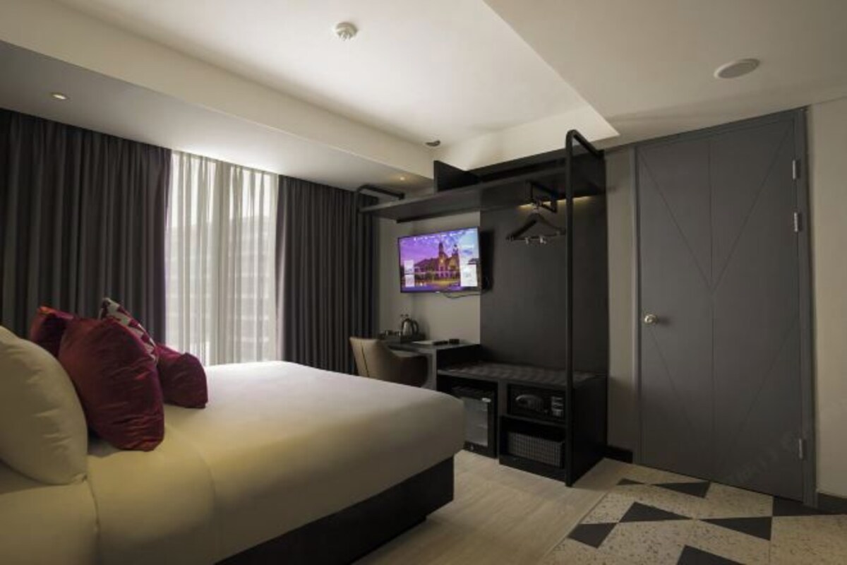 Une chambre d’hôtel moderne équipée d’un grand lit, d’un bureau avec un ordinateur, d’une télévision et d’une armoire.