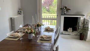 A dining room with a wooden table set for four, a fireplace, and a view of the garden through a door. - Magnolia Home Lucca Campagna (Capannori)