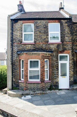 A two-story brick house with a white door and two windows on the ground floor. - Charming Boutique House – Stylish Stay Just Minutes from Margate Beach (Kent)
