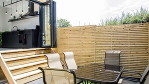 Un patio exterior con una mesa de comedor y sillas, una parrilla y una cocina con ventana.