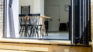 Un interior moderno con comedor, una escalera que lleva a un balcón y vistas al exterior.