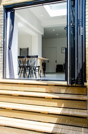 A modern interior with a dining area, a staircase leading to a balcony, and a view of the outside. - Charming Boutique House – Stylish Stay Just Minutes from Margate Beach (Kent)