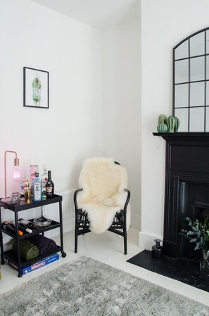 A living room with a white armchair, a black fireplace, and a shelf with various items. - Charming Boutique House – Stylish Stay Just Minutes from Margate Beach (Kent)
