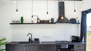 Una cocina moderna con estufa a gas, armarios negros, encimera negra e iluminación colgante.