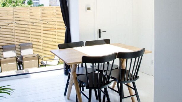 Un comedor moderno con una mesa y sillas, vistas al exterior y una puerta que conduce a otra habitación.