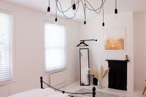A bedroom with a bed, a mirror, a fireplace, and hanging lights. - Charming Boutique House – Stylish Stay Just Minutes from Margate Beach (Kent)