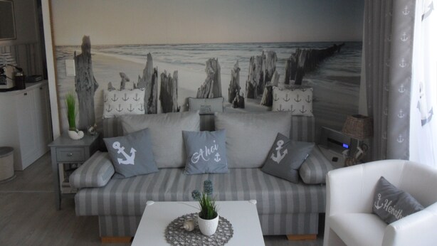 A living room with a beach-themed mural, a striped sofa, and a white armchair.