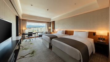 Une chambre d’hôtel avec deux lits, un bureau, une télévision et une vue sur la ville.