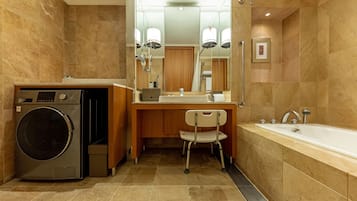 A modern bathroom with a built-in washer, a vanity with a mirror, a chair, and a bathtub.