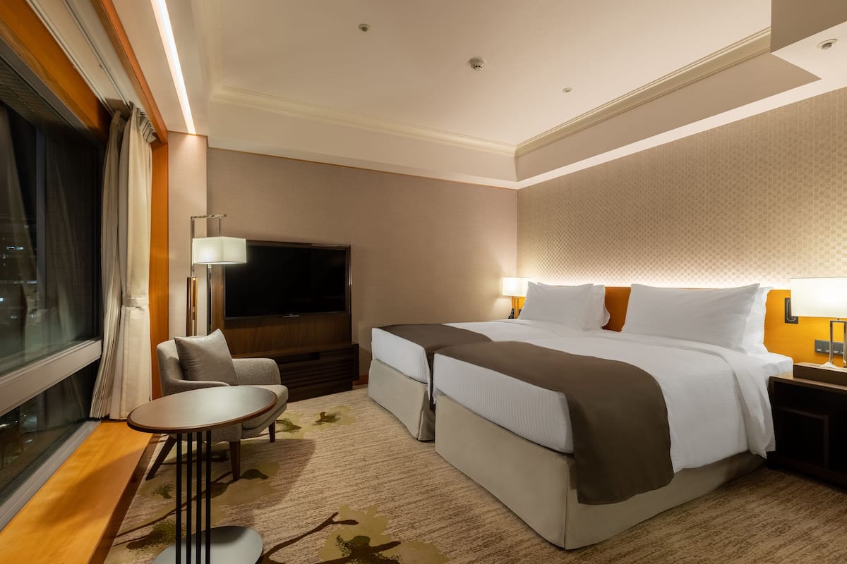 A hotel room with a large bed, a TV, a desk, and a chair.