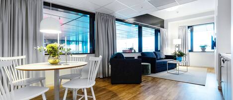 Ett modernt vardagsrum med en matplats, stora fönster och en blå soffa.