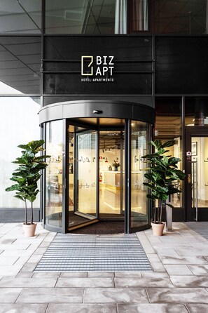 A modern hotel entrance with a revolving door, potted plants, and a tiled floor. - Biz Apartment Bromma (Bromma)
