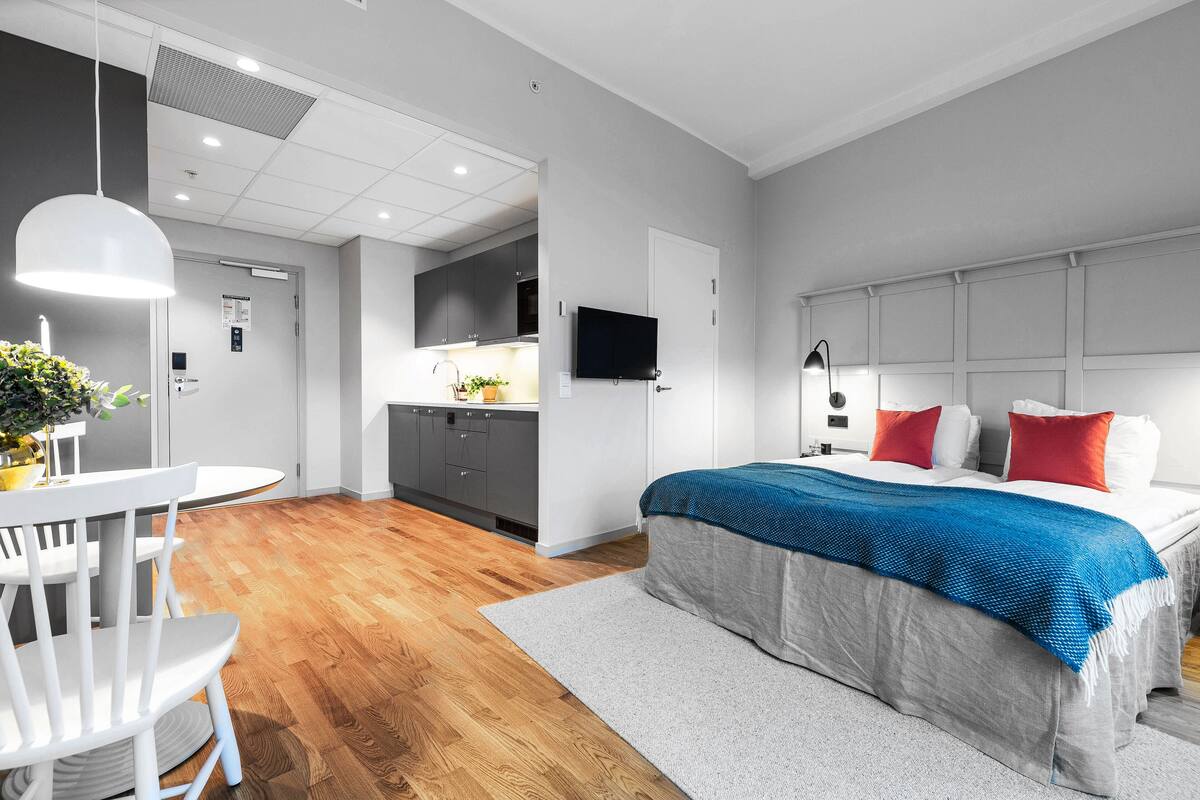 Una habitación de hotel moderna con una cama grande, un escritorio y una kitchenette.