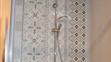 Une douche équipée d’un pommeau de douche à main et d’un flexible de douche.